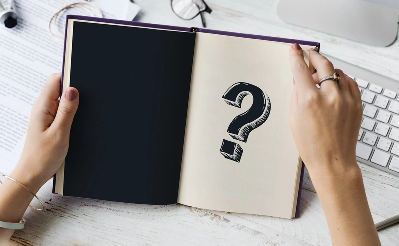 a man opens a book marked with a question mark