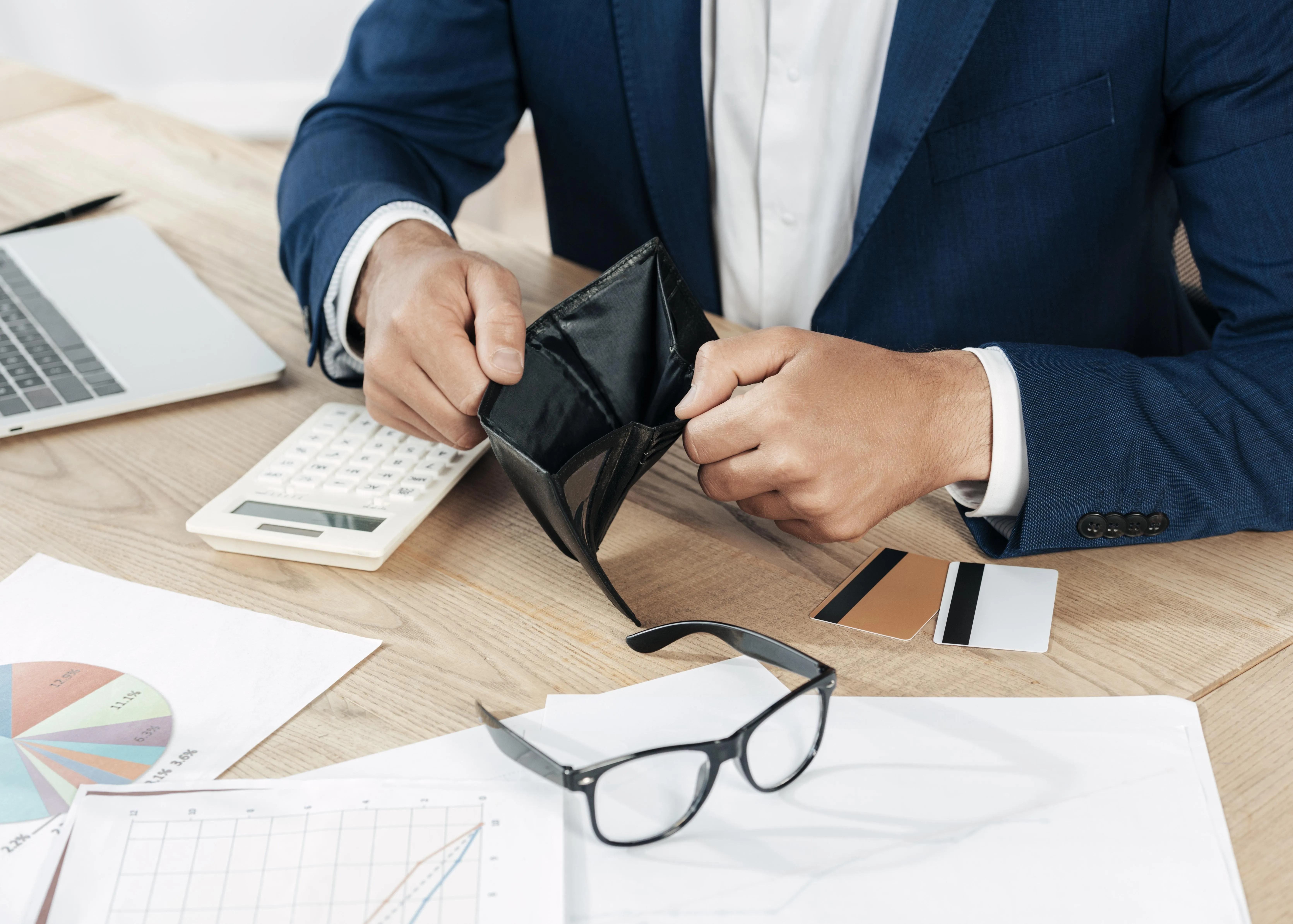 a man opens an empty wallet on a chaotic table